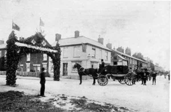 Carriage passing through arch in front of The Swan